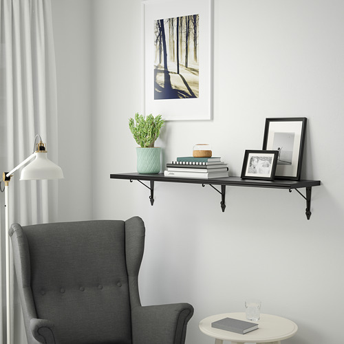 Estantería de pared BERGSHULT, negro. Sostiene libros, marcos y plantas. Montado en lo alto de una acogedora silla gris. Diseño ligero y delgado.