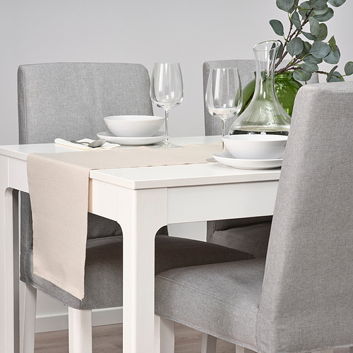 Mesa de comedor blanca con sillas grises; Conjunto con cuencos, platos, copas de vino y jarrón verde con plantas.