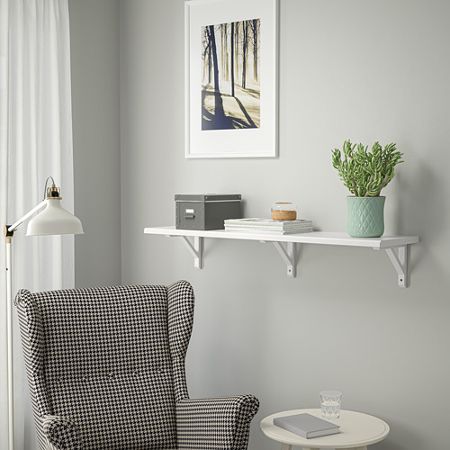 Estantería TRANHULT sobre sillón pata de gallo con decoración. La sencillez moderna se une a la comodidad acogedora.