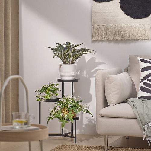 Modern living room with plant, armchair, patterned pillows, side table, and wall art.
