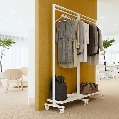 Perchero MITTZON con ropa y bolsos, pared mostaza, sillas de madera.