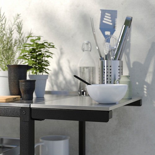 Encimera de cocina con tazón, utensilios y plantas. Diseño moderno, negro y plateado.