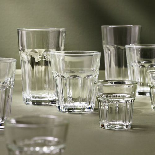 Varios vasos transparentes POKAL de diferentes tamaños, hechos de vidrio templado, exhibidos sobre un mantel verde, mostrando su diseño clásico y durabilidad.