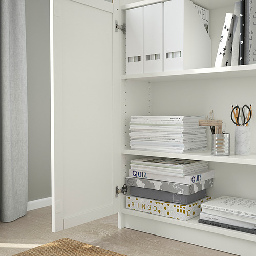 White BILLY bookcase with adjustable shelves, holding storage boxes, game sets, and stationery.