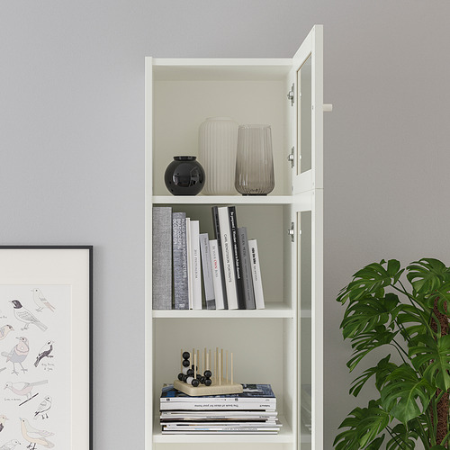 Librería blanca con tres estantes: jarrones, libros, plantas.