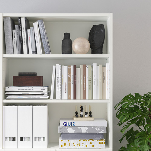 Librería blanca con estantes ajustables, con varios libros, artículos decorativos y juegos.