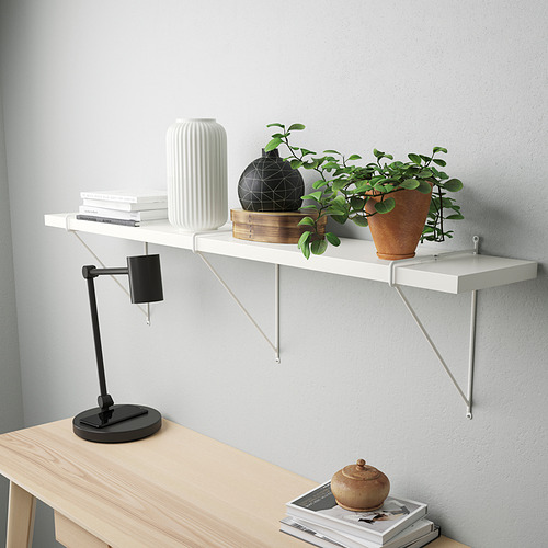 Estantería de pared minimalista con libros, lámpara, jarrón y planta.
