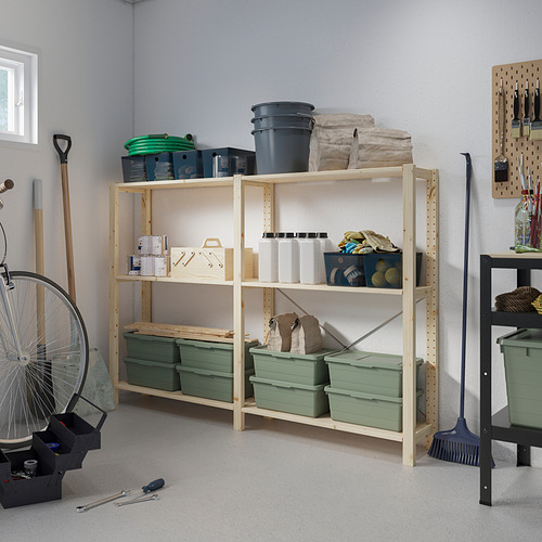 Grandes estantes de madera IVAR de color claro con contenedores de plástico verde en el garaje, rodeados de diversas herramientas y equipos.