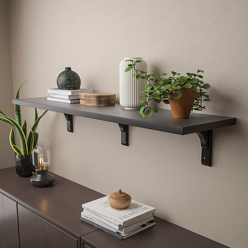 El estante de pared con soportes negros sostiene artículos decorativos como plantas, libros y jarrones.
