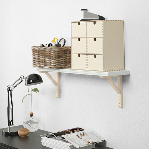 Estantería de pared con cajones, material de oficina y cesta de mimbre. Una lámpara de escritorio y revistas debajo.