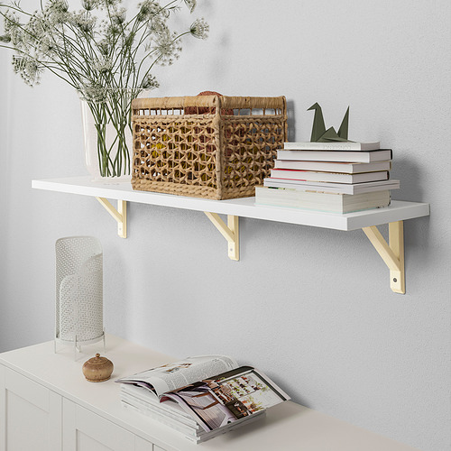 Estante de pared blanco montado con 3 soportes. Exhibiendo libros, canasta tejida, jarrón con flores y una pila de revistas.