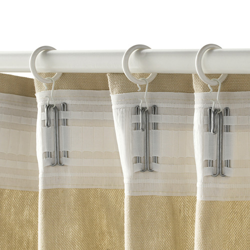 Tres cortinas beige cuelgan de varilla blanca mediante clips y ganchos en anillos.