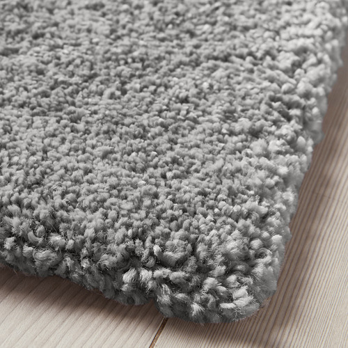 Esta imagen muestra una alfombra gris de felpa sobre un suelo de madera. Las alfombras densas y suaves de pelo añaden comodidad y amortiguan el ruido, realzando la calidez de las habitaciones.