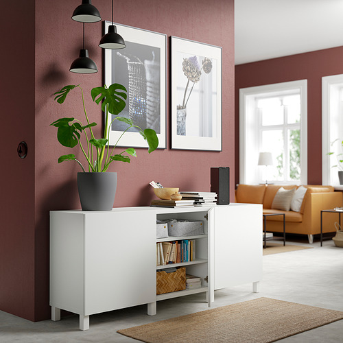 Sala de estar moderna con almacenamiento BESTÅ, libros, decoración, planta. Muro burdeos, arte, luces.