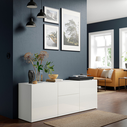 Sala de estar con aparador BESTÅ, sofá naranja, lámparas, fotos, flores, suelo de madera, ventanas.