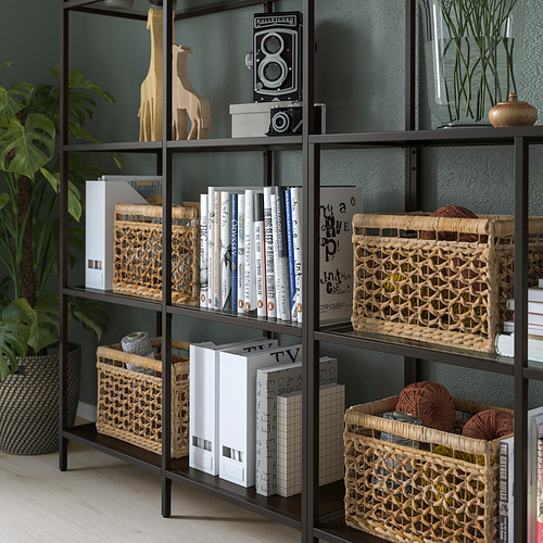 Estantes de metal negro con vidrio, exhibiendo libros, cestas decorativas y esculturas de jirafas.