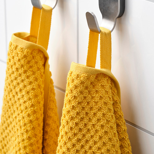 Dos toallas de color amarillo brillante cuelgan cuidadosamente de ganchos, mostrando su material de algodón suave y texturizado y prácticas perchas de bucle.