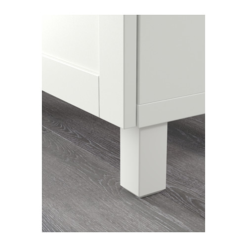 Pata de armario blanca sobre suelo de madera gris, con una base robusta y un diseño elegante.
