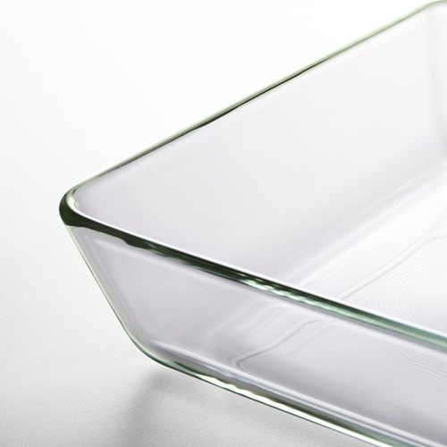 Bandeja para hornear de vidrio transparente con bordes suavemente curvados, que descansa sobre una superficie blanca.