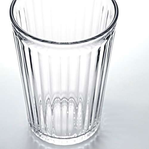 El vaso de vidrio transparente y estriado se muestra en posición vertical, vacío. Diseño simplista, duradero, transparente y elegante.