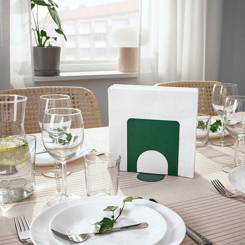 Mesa de comedor con vasos, platos y servilletero, decorada con manteles y plantas.
