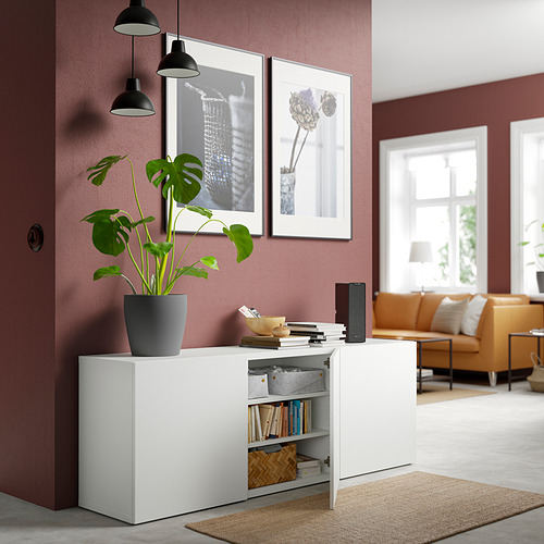 Sala de estar moderna con almacenamiento BESTÅ blanco. Tiene estantes ajustables, puertas de cierre suave y una planta en la parte superior.