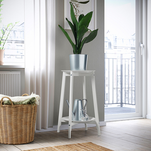 Soporte de planta de acero de madera blanca ALPVIDE, bandeja gris, sosteniendo planta verde alta cerca de la cesta, puerta, ventana.