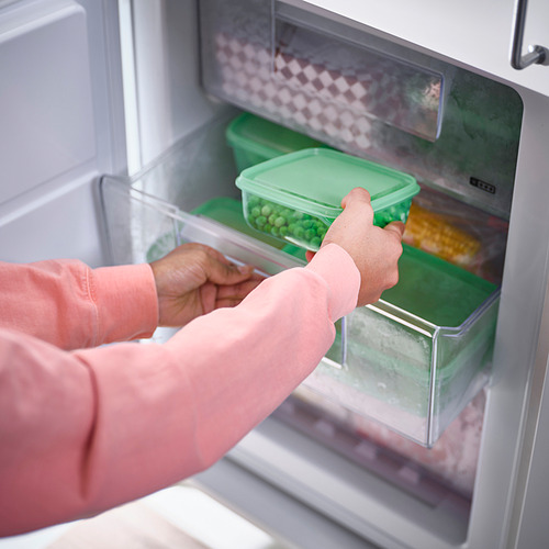 Persona que abre una nevera para acceder a recipientes de plástico de almacenamiento de alimentos de diferentes tamaños que se utilizan para almacenar las sobras y ahorrar espacio durante el almacenamiento.