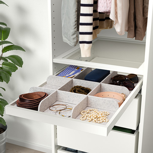 Cajón organizado con compartimentos para cinturones, joyas y accesorios dentro de un armario.