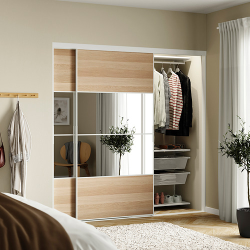 Dormitorio con closet corredizo con espejo SKYTTA, camisa a rayas, chaqueta, planta, cortinas finas, paredes beige.