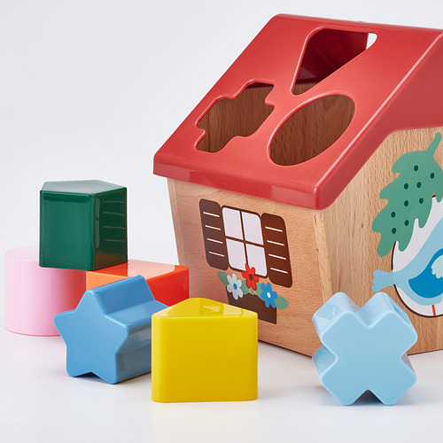 Colorida casa de juguete de madera con varias formas alrededor: rojo, amarillo, azul y verde. Un juguete educativo divertido y atractivo para los niños.