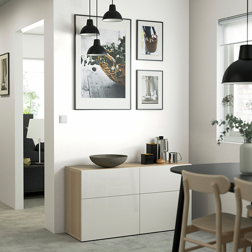Modern dining: BESTÅ sideboard with photos, decor. Black lights, wooden chairs. Doorway to living area with couch, lamp.