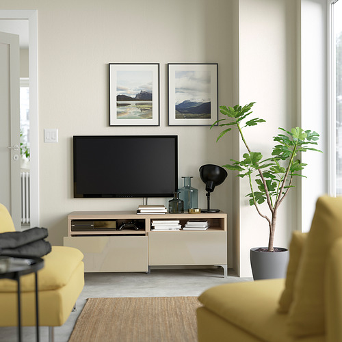 Living room with yellow couch, flat screen tv, NANNARP tv bench, two framed mountain photos, and a potted plant.