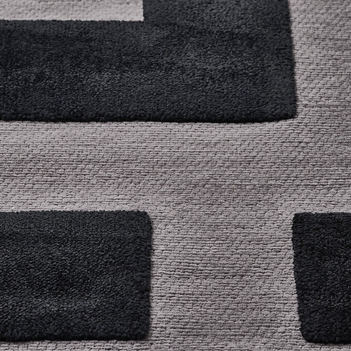 Alfombra geométrica texturizada con cuadrados gruesos y suaves en negro y gris claro, que ofrece un diseño moderno y cómodo.
