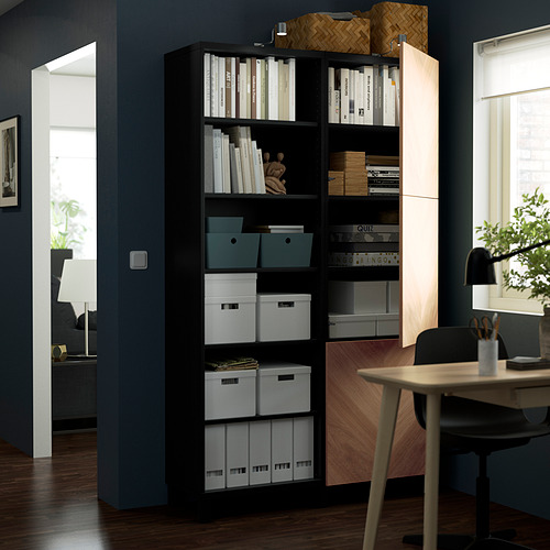 Mueble BESTÅ negro con estantes ajustables para libros, cajas y decoración; Los estantes abiertos exhiben artículos, las secciones cerradas ocultan el almacenamiento.