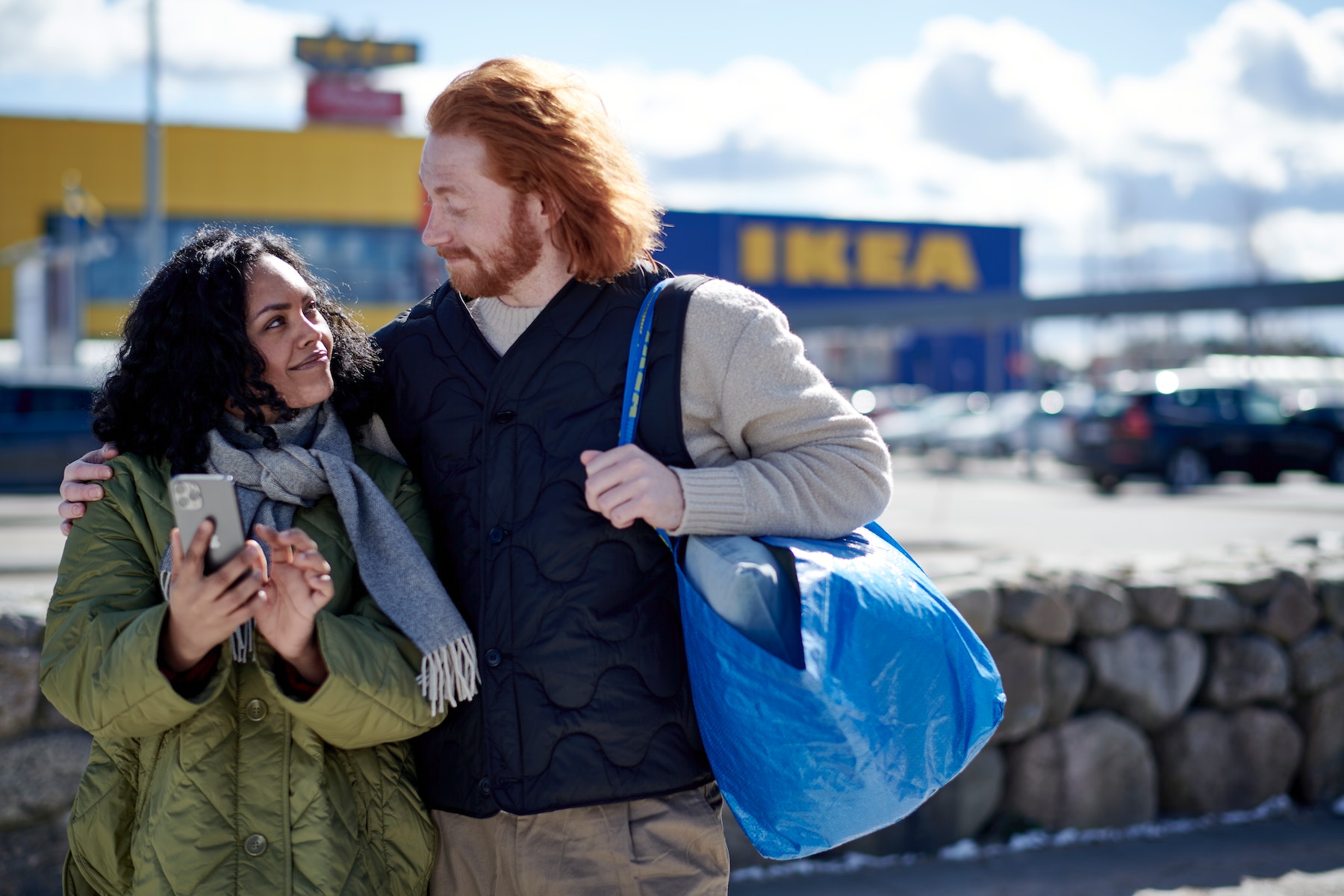 Pareja sonriente con bolsa azul de IKEA frente a la tienda.