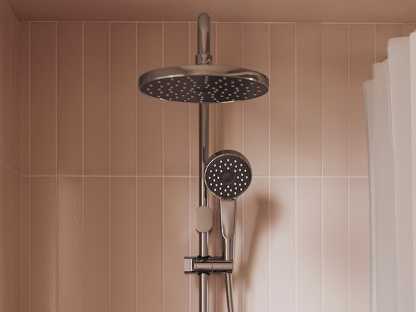 Chrome shower set with fixed overhead spray and hand shower against beige tiles.