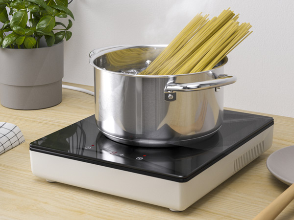 Stainless steel pot boiling spaghetti on a portable induction cooktop.