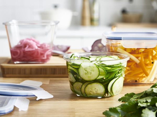 Glass food containers filled with pickled vegetables on a kitchen counter.