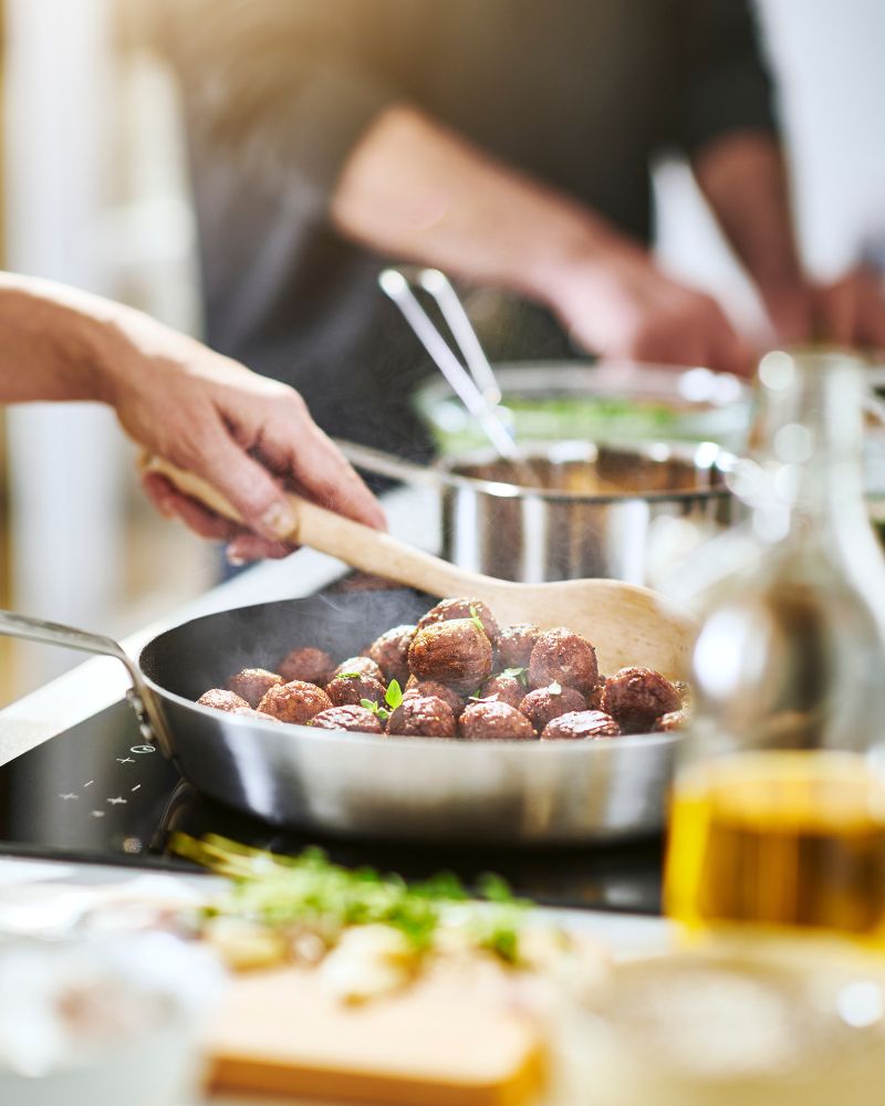 Active home kitchen with hands-on cooking featuring HEMKOMST frying pan and HUVUDROLL vegetable balls on MATMÄSSIG induction