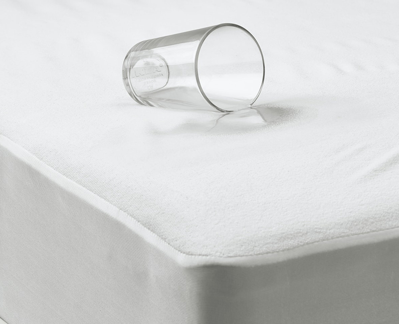 Glass on a white mattress protector, showing its waterproof quality. Simple, clean design.