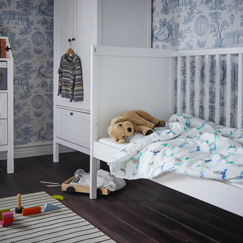 A baby room with a SUNDVIK crib on the right with a GOSIG GOLDEN stuffed animal on top, and a SUNDVIK wardrobe.