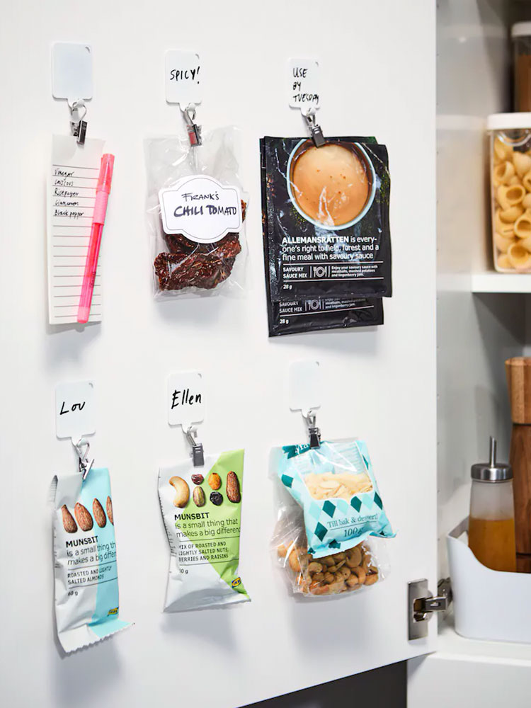 Open pantry door with hanging spice packets on hooks, showcasing a variety of seasonings in a rustic kitchen setting.
