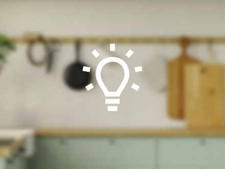 White vector drawing of an illuminated light bulb with background of a traditional kitchen completely blurred.