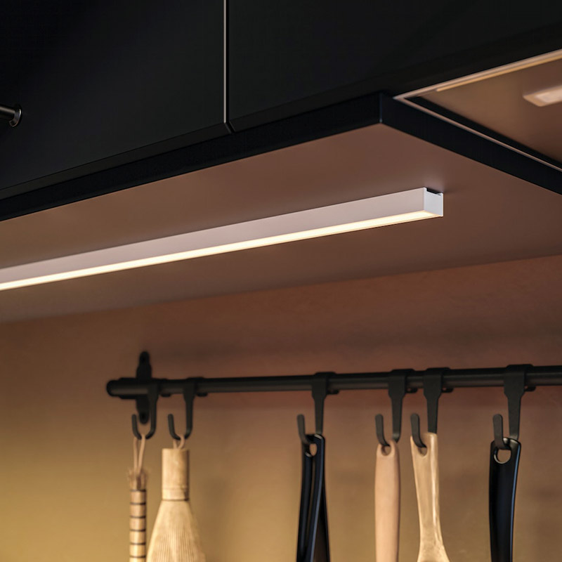 LED lighting under black kitchen cabinets, with utensils hanging on a dark bar below.