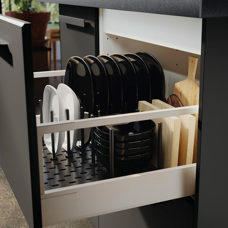 Organized kitchen drawer with black and white plates, bowls, and wooden cutting boards.