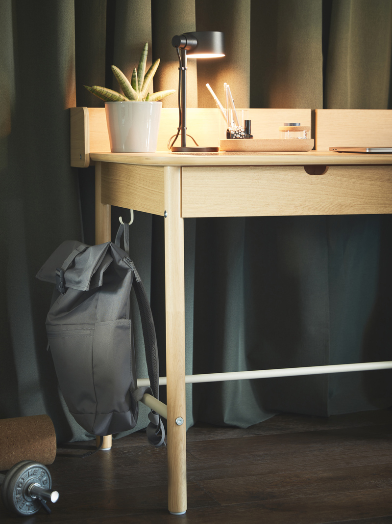 A RIDSPÖ desk seen from underneath with dark TIBAST curtains in the background.