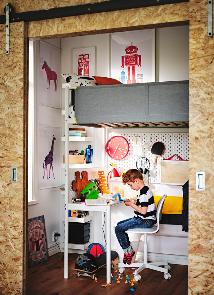 A child's room with light walls, a gray loft bed, a white desk with a chair, and colorful decorations. Creative and organized atmosphere.