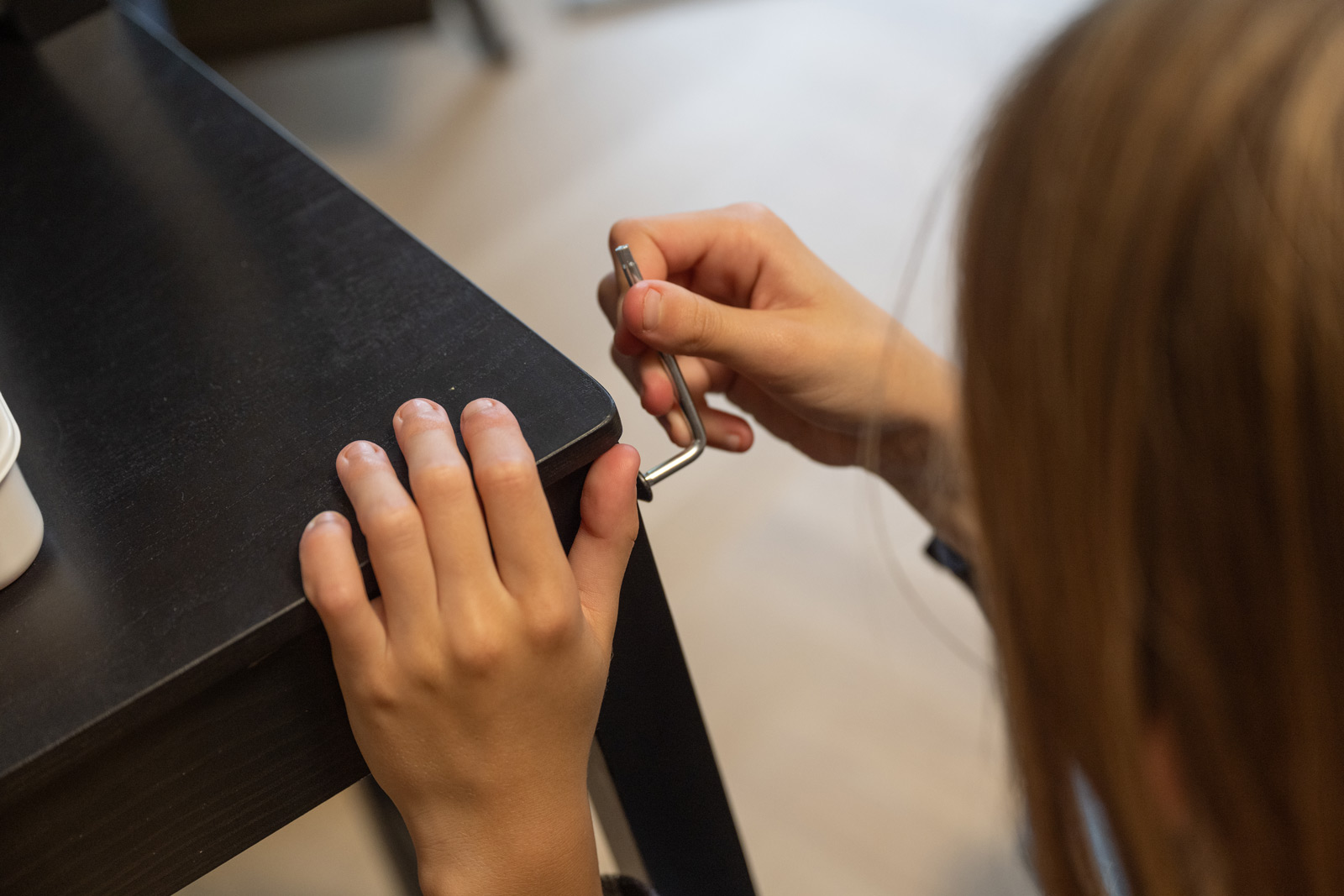 Person using Allen wrench to assemble black table