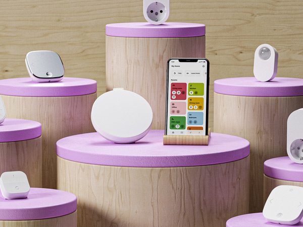Smart home devices and smartphone displayed on wooden pedestals with pink tops.